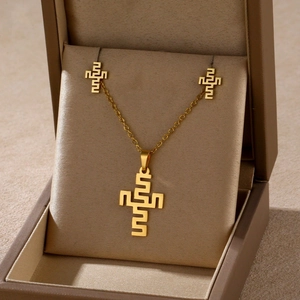 Detailed view of golden cross jewelry set with geometric pattern in a premium gift box
