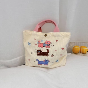 Détail du sac en velours côtelé crème avec poignées roses et broderie chaton et bouton-pression