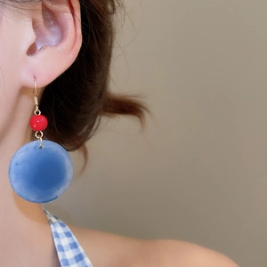 Mannequin portant des boucles d'oreilles géométriques en acrylique à pompons bleus