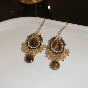 Detailed macro view of vintage gold earrings with tiger eye stone and bead tassels