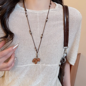 Gros plan d'un collier pendentif chien teddy marron avec perles argentées sur un mannequin