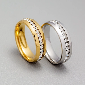 Macro shot of gold and silver channel-set zircon rings on a grey leather surface