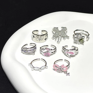 Minimalist open rings set with butterfly, bow, and zircon stones on a white tray