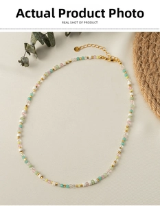 Detail of colorful beaded necklace with natural stones and gold lobster clasp on fabric