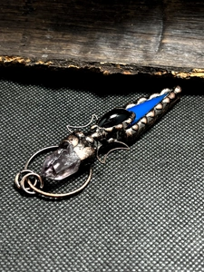 Detailed close-up of a vintage bronze moon pendant with agate arrow and raw amethyst crystal