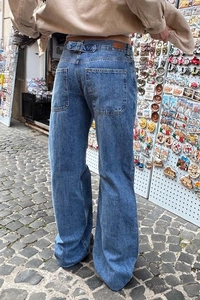 Street style view of high waisted washed blue wide leg denim pants from the back