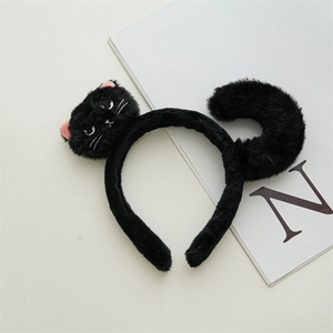 Detail of a soft black plush cat headband with cartoon ears and a tail on a magazine