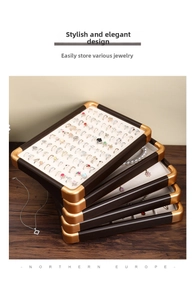 Detail of stacked walnut jewelry trays with beige velvet lining and gold metal corners