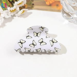 Detailed view of a white acrylic hair claw clip with yellow and black butterfly prints