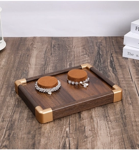 Detail view of walnut wood jewelry tray with gold metal corners and velvet ring inserts