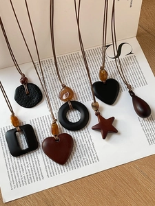Détail de pendentifs bohèmes géométriques en forme de cœur et d'étoile sur cordon brun