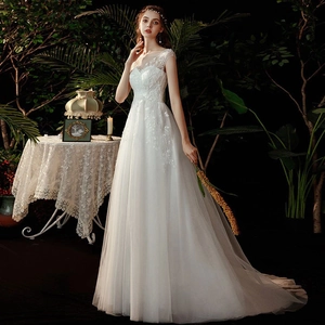 Elegant white lace wedding dress with sheer sleeves and sequin embroidery in a forest setting