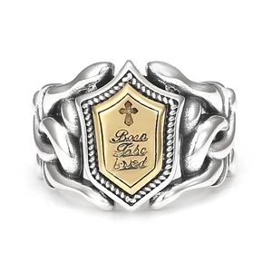 Close-up of vintage shield ring with golden cross relief and engraved lettering details
