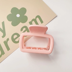 Detail of pink matte rectangular hair claw clip with cutout design on a white background