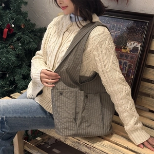 Detail of coffee-grey plaid tote bag with retro metal buckle in cozy Christmas setting