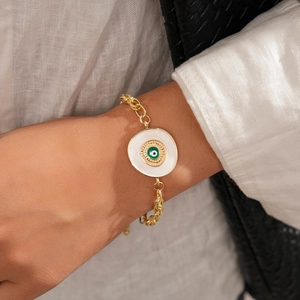 Détail d'un bracelet chaîne doré avec breloque œil porte-bonheur porté par un mannequin