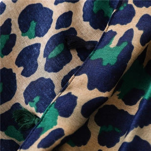 Macro shot of cotton linen scarf with blue leopard print and decorative tassels