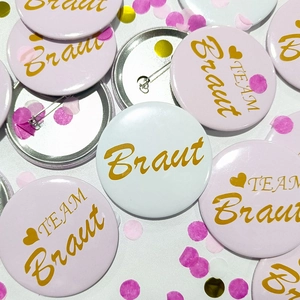 Pink and white Bride to Be tinplate badges with German text for wedding party decor