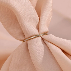 Macro shot of 18K gold-plated slim ring with micro-pave zircons on soft pink silk