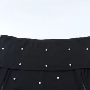 Détail de l'encolure à épaules dénudées avec perles élégantes sur tissu noir à mailles côtelées