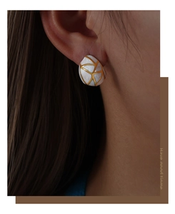 Close-up of geometric enamel earring with gold line texture on a model's ear