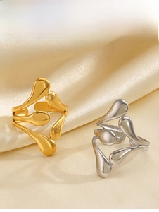 Polished gold and silver fluid teardrop rings displayed on elegant silk background