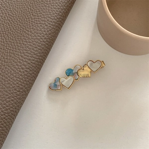 Detailed close-up of heart-shaped hair clip with champagne gold and marble textures