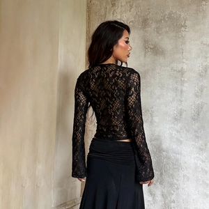 Détail du haut en dentelle noire à manches longues avec motifs floraux et poignets évasés