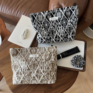 Detailed view of handmade embroidered cotton linen cosmetic bags on a rustic wooden table