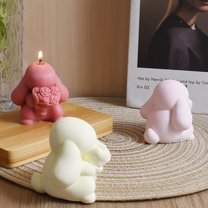 Detailed view of handmade bunny aroma candles with rose bouquets on a wooden base