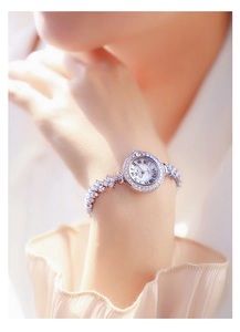 Detail of luxury silver women's watch with rhinestone bracelet and Roman numeral dial