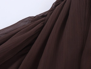 Macro shot of dark brown pleated chiffon fabric with elegant texture and soft drape