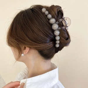 Close-up of a large grey resin hair claw clip with marble beads on long brown hair