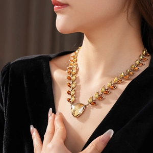 Détail du collier vintage doré avec gemme cœur ambre et motifs de feuilles