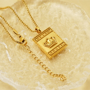 Close-up of golden stainless steel necklace with a crown pendant on a luxury background