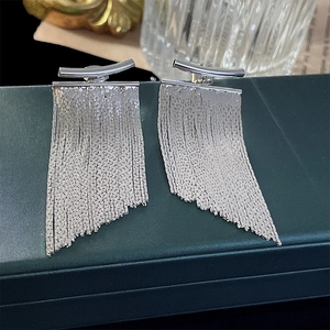 Detail shot of silver tassel earrings with fine metal chains on a dark green jewelry box