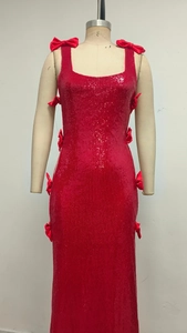 Detail of red sequin party dress featuring satin bow accents and shimmering texture
