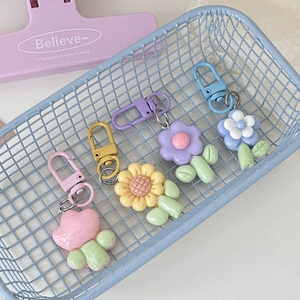 Close-up of colorful floral keychains in pink, yellow, blue, and purple in a metal basket