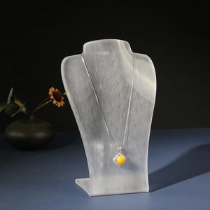 Acrylic jewelry stand with silver necklace featuring a yellow amber pendant and diamonds