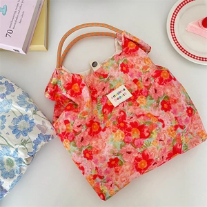 Detail of floral tote bag showing artistic print, rope handle, and metal magnetic closure