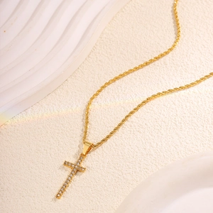 Macro detail of a gold cross pendant featuring pave zircons and a twisted rope chain