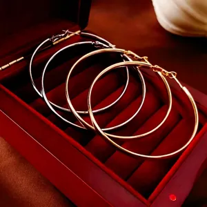 Grandes boucles d'oreilles créoles minimalistes en or et argent sur velours rouge