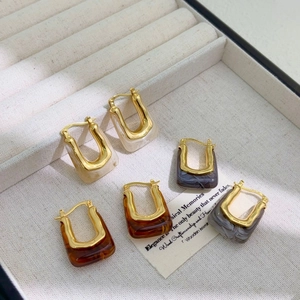 Detail of vintage U-shaped gold earrings with marble and amber resin textures