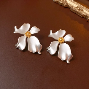 Detail of vintage flower earrings with matte white petals and golden center on leather