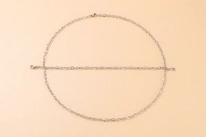 Detail of silver O-link chain showing circular and straight link textures on beige background