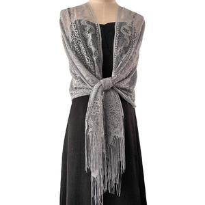Close-up of grey lace shawl featuring floral hollow-out patterns and delicate long tassels