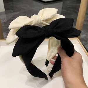 Detail of corduroy bow headbands in black and cream beige with ribbed texture