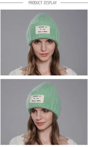 Detail view of light green knit beanie with woven letter patch and premium texture