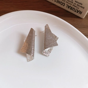 Detailed view of irregular geometric silver earrings with textured brushed metal finish