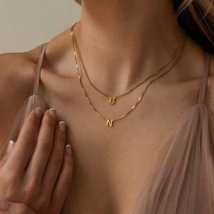 Détail d'un collier doré à deux rangs avec pendentifs lettres B et N pour femmes